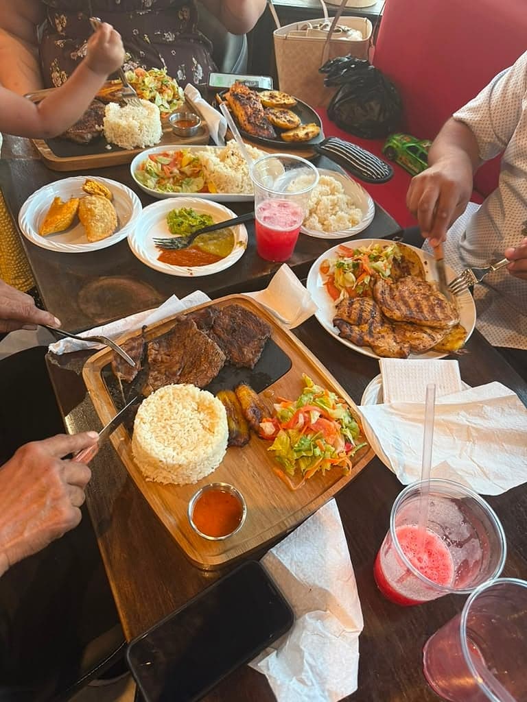 Family-style table spread of parrillada, rice, salad and empanadas