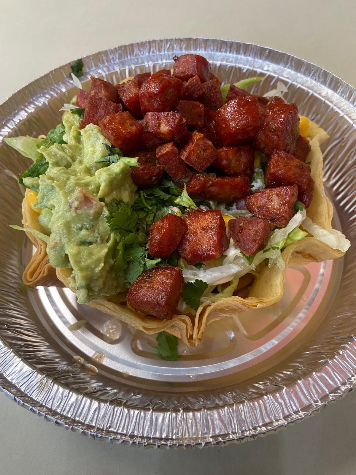 Crispy tostada bowl topped with chorizo, guacamole and pico de gallo